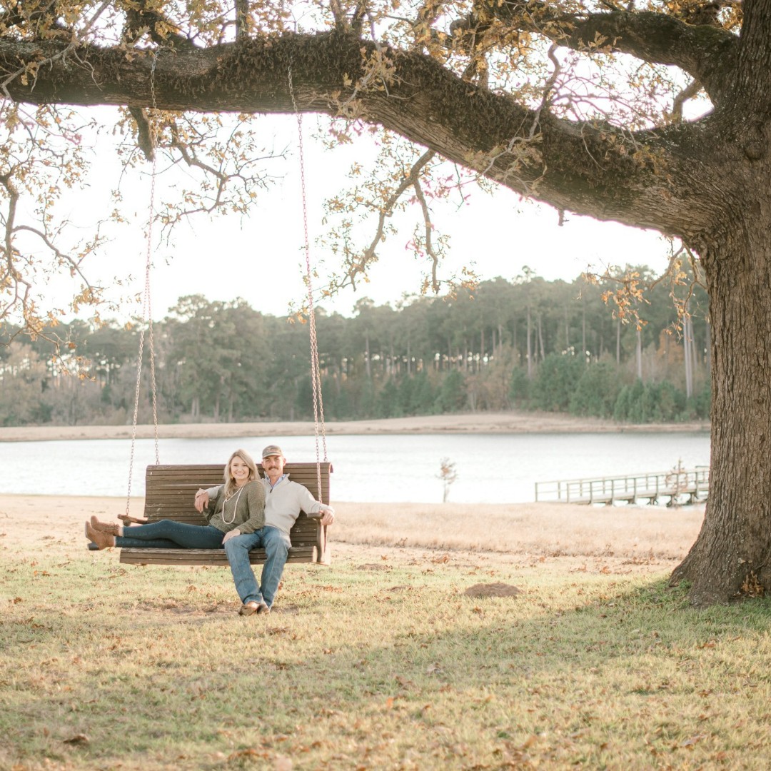 engaged couple sitting on a swing