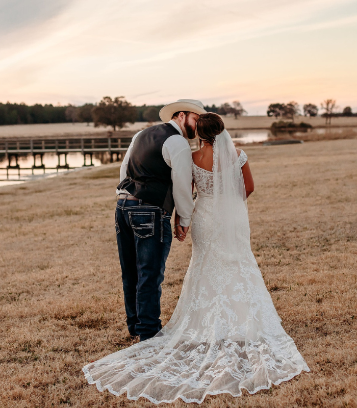 bride and groom kissing on open pasture 